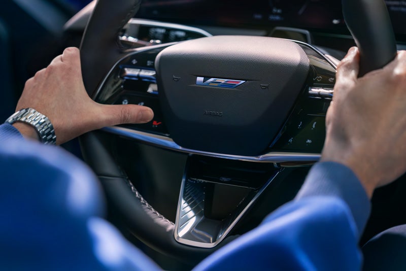 Close-up of a Man About to Press the V-Button on the 2026 OPTIQ-V Steering Wheel | Faulkner Cadillac Trevose in TREVOSE PA