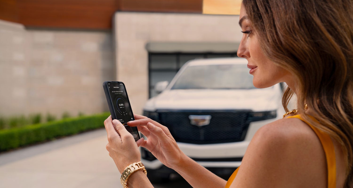 lady checking her mobile with a Cadillac vehicle background | Faulkner Cadillac Trevose in TREVOSE PA