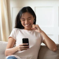 woman on couch dialing cell phone