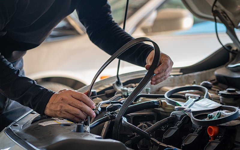 mechanic fixing a belt in car engine