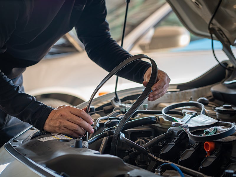 mechanic putting a new belt on car engine